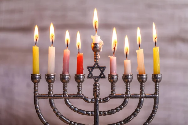Jewish holiday Hanukkah. Menorah with candles for Hanukkah on a light wooden background. Front view