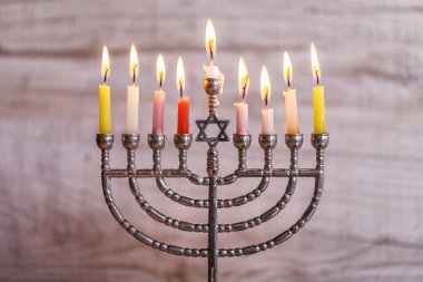 Jewish holiday Hanukkah. Menorah with candles for Hanukkah on a light wooden background. Front view clipart