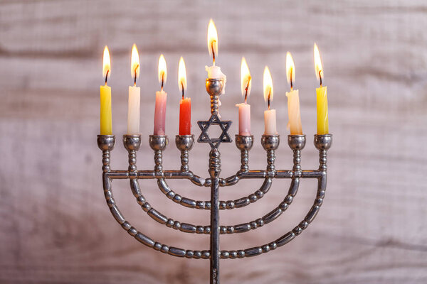 Еврейский праздник Ханука. Менора со свечами для Хануки на светлом деревянном фоне. Вид спереди
