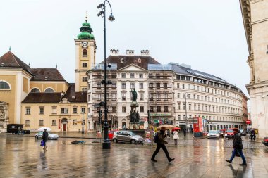 VIENNA, AUSTRIA - MAY 22, 2019: This is Freyung Square in front of the Scottish Monastery with Austria fountain in the middle of the square on a rainy spring day.