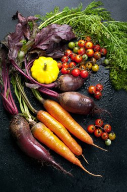 Parlak sulu tarım ürünleri (sebze): pancar, havuç, domates ve sarı kabak koyu arka plan üzerinde. Vejetaryen vegan kavramı. Ham organik ürünleri.