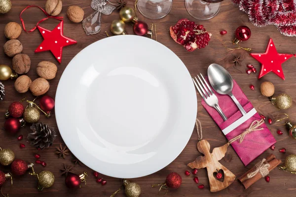 クリスマスのおもちゃ、クルミ、星アニスとシナモンと新年と茶色の木製の背景にクリスマスの他の属性の近くに (任意のお祝い料理に合わせて) 空白い板。お祝い料理 (料理休日の供給の概念 — ストック写真