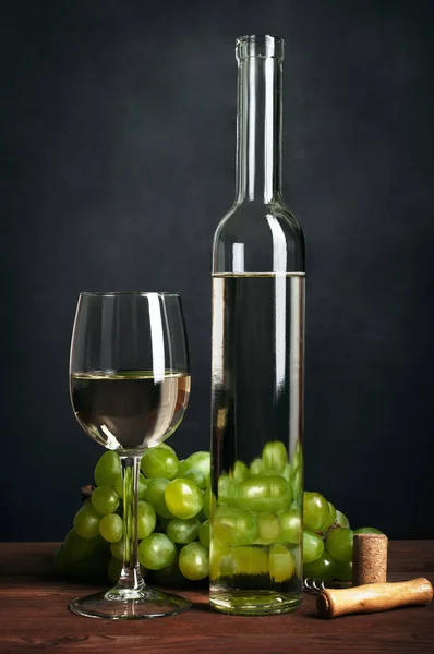 Бутылка и стакан сухого белого вина на коричневой деревянной доске, черный фон. Концепция культуры потребления вина. Алкогольные напитки — стоковое фото