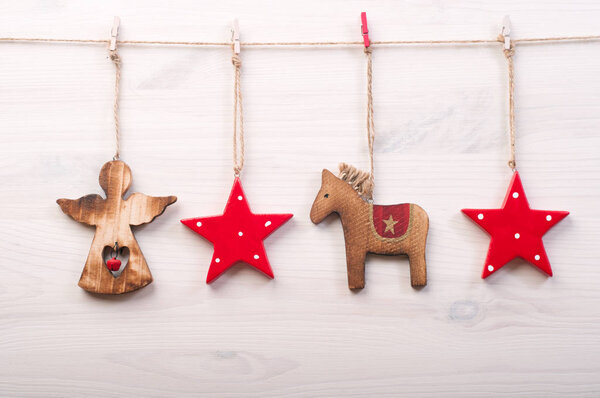 Christmas and New Year wallpaper (background). Christmas toys in a Scandinavian style, such as red stars, a horse and an angel on a white wooden surface.