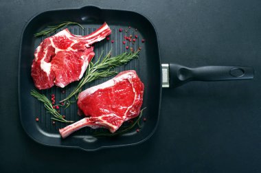 Ham sığır eti biftek (adet et) bir ızgara üzerinde karanlık bir arka plan üzerinde pan. Metin için yer