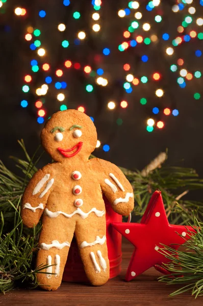 Noël et Nouvel An papier peint (fond). Homme roux qui se tient à côté d'une étoile rouge et branches de pin sur un fond guirlandes incluses. Lumière naturelle — Photo