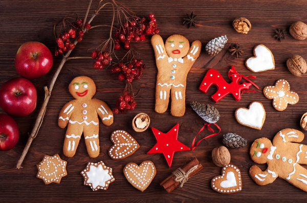 Christmas and New Year wallpaper (background).  Gingerbread man, Christmas toys and decorations, nuts, cinnamon, anise and other attributes of Christmas on brown wooden background.