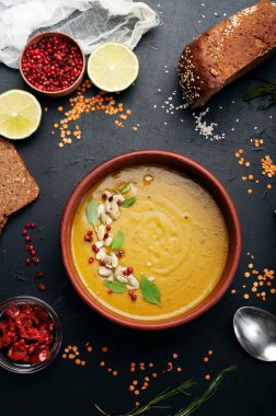 Biberiye, zira, nane ve koyu arka plan üzerinde kahverengi hamurlu tabak içinde diğer baharatlar ile mercimek çorbası. Yakın tahıl kırmızı mercimek, baharat ve baharat, çavdar ekmeği, sebze. Vejetaryen, vegan kavramı