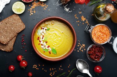 Biberiye, zira, nane ve koyu arka plan üzerinde kahverengi hamurlu tabak içinde diğer baharatlar ile mercimek çorbası. Yakın tahıl kırmızı mercimek, baharat ve baharat, çavdar ekmeği, sebze. Vejetaryen, vegan kavramı