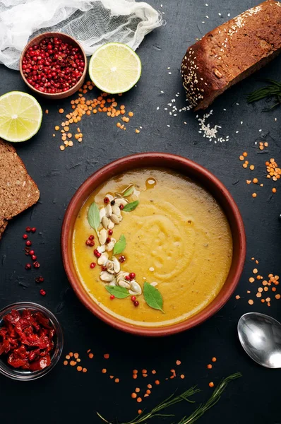 Lentil soup with rosemary, zira, mint and other spices in brown earthenware plate on dark background. Close grain red lentils, spices and seasonings, rye bread, vegetables. Vegetarian, vegan concept — Stock Image Lentil soup with rosemary, zira, mint and other spices in brown earthenware plate on dark background. Close grain red lentils, spices and seasonings, rye bread, vegetables. Vegetarian, vegan concept Royalty Free Stock Images