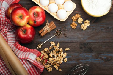 Mutfak arka plan: elmalı turta yapmak için gerekli malzemeler. Sulu Kırmızı elma, yumurta, un, fındık ve baharat kahverengi ahşap arka plan mavi boya ile. Vejetaryen kavramı. Metin için yer