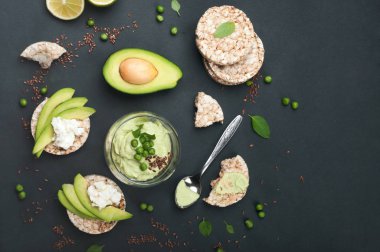 Guacamole - avokado hamuru soğuk meze - karanlık bir arka plan üzerine bir bardak. Avokado ve krem peynir dilimleri ile pirinç ekmek yanında. Meksika mutfağı. Vejetaryen, vegan kavramı 