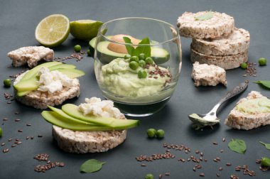 Guacamole - avokado hamuru soğuk meze - karanlık bir arka plan üzerine bir bardak. Avokado ve krem peynir dilimleri ile pirinç ekmek yanında. Meksika mutfağı. Vejetaryen, vegan kavramı 