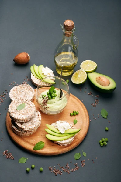 Guacamole - avokado hamuru soğuk meze - karanlık bir arka plan üzerine bir bardak. Avokado ve krem peynir dilimleri ile pirinç ekmek yanında. Meksika mutfağı. Vejetaryen, vegan kavramı — Stok fotoğraf