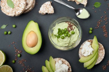 Guacamole - avokado hamuru soğuk meze - karanlık bir arka plan üzerine bir bardak. Avokado ve krem peynir dilimleri ile pirinç ekmek yanında. Meksika mutfağı. Vejetaryen, vegan kavramı 
