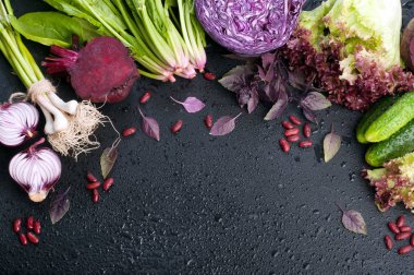Sebze arka planı (duvar kağıdı). Parlak sulu mor ve yeşil sebze ve otlar su damlaları siyah bir zemin üzerine. Kırmızı lahana, mor soğan, ıspanak, marul, salatalık ve fesleğen. Metin için yer. Vejetaryen, vegan kavramı