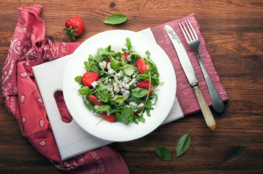 Roka, çilek, mavi peynir ve zeytin yağı beyaz tabakta salatası. Düşük kalorili diyet sağlıklı yemek. Mevsimlik ürünler.