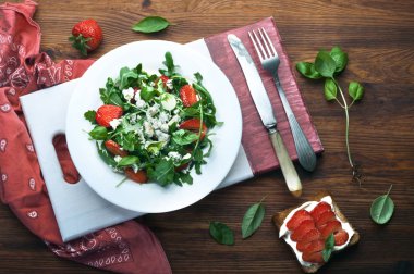 Roka, çilek, mavi peynir ve zeytin yağı beyaz tabakta salatası. Düşük kalorili diyet sağlıklı yemek. Mevsimlik ürünler. Tost, az yağlı yumuşak peynir ve çilek sandviçle kapatın.