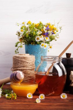 Farklı renklerle bir kahverengi ahşap tahta üzerinde farklı kapasitelere tatlım. Kır çiçekleri buketi. Beyaz ahşap zemin.