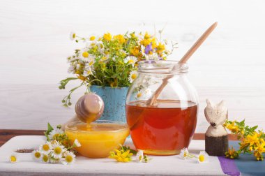 Farklı renklerle bir kahverengi ahşap tahta üzerinde farklı kapasitelere tatlım. Kır çiçekleri buketi. Beyaz ahşap zemin.