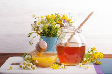 Farklı renklerle bir kahverengi ahşap tahta üzerinde farklı kapasitelere tatlım. Kır çiçekleri buketi. Beyaz ahşap zemin.