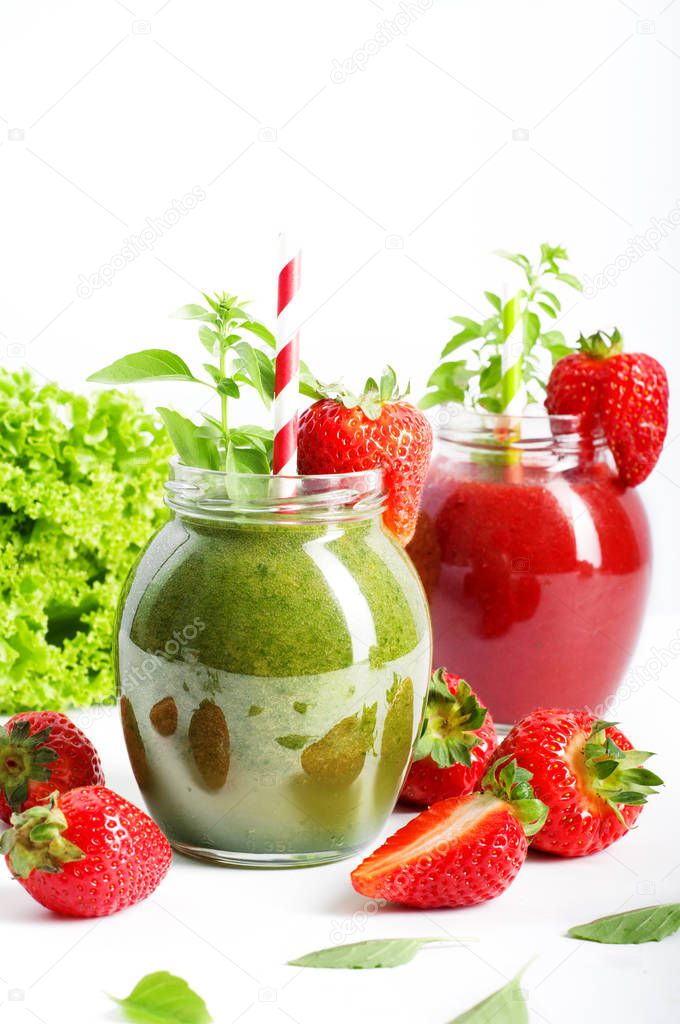 Green smoothie of apples, spinach and avocado in a pot on a white surface. In the background of strawberry smoothie. Near lettuce and strawberries. Space for text. Vegan, vegetarian diet low calorie seasonal drink