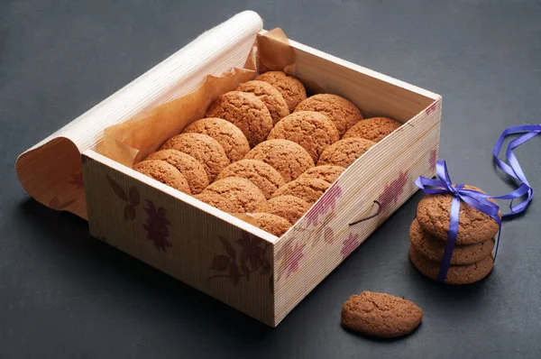 Galletas de avena en una caja sobre un fondo oscuro. Dulces útiles —  Fotos de Stock