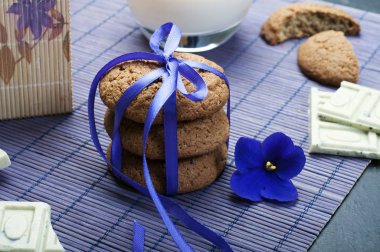 Yulaflı kurabiyeler, mor mat mor kurdele ile bağlanmış yığını. Makro vurdu. Arka plan bulanık. Beyaz çikolata ve bisküvi arka plan parçalar halinde