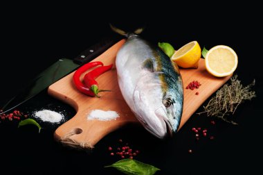 Kavurma tarafından hazırlanan ham ton balığı (bütün balık) mı yalan ahşap kesme tahtası üzerinde limon, otlar ve baharatlar kapatın. Evde yemek tarifleri beslenme (konsept).