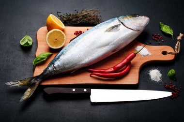 Kavurma tarafından hazırlanan ham ton balığı (bütün balık) mı yalan ahşap kesme tahtası üzerinde limon, otlar ve baharatlar kapatın. Evde yemek tarifleri beslenme (konsept).