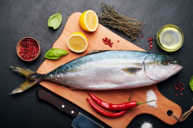 Kavurma tarafından hazırlanan ham ton balığı (bütün balık) mı yalan ahşap kesme tahtası üzerinde limon, otlar ve baharatlar kapatın. Evde yemek tarifleri beslenme (konsept).