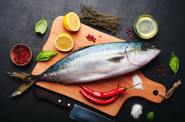 El atún crudo (pescado entero) preparado asando, se encuentra en una tabla de cortar de madera, cerca de limón, hierbas y especias. Recetas de nutrición en casa (concepto ). — Foto de Stock