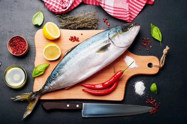 El atún crudo (pescado entero) preparado asando, se encuentra en una tabla de cortar de madera, cerca de limón, hierbas y especias. Recetas de nutrición en casa (concepto ). — Foto de Stock