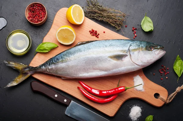 Сырой тунец (целая рыба), приготовленная на обжаривании, лежит на деревянной доске, закрытой лимоном, травами и специями. Рецепты питания на дому (концепция ). — стоковое фото