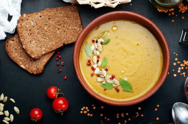 Krem koyu arka plan üzerinde bir kahverengi hamurlu tabak içinde kırmızı mercimek çorbası. Çevre çavdar ekmeği, barbunya ve susam chechetsy. Diyet vejetaryen yemek. Bitmiş çanak