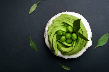 Avokado dilimleri, krem peynir ve pirinç kek karanlık bir arka plan üzerinde diyet kalori sandviç. Organik ürünlerin bir aperatif. Metin için yer