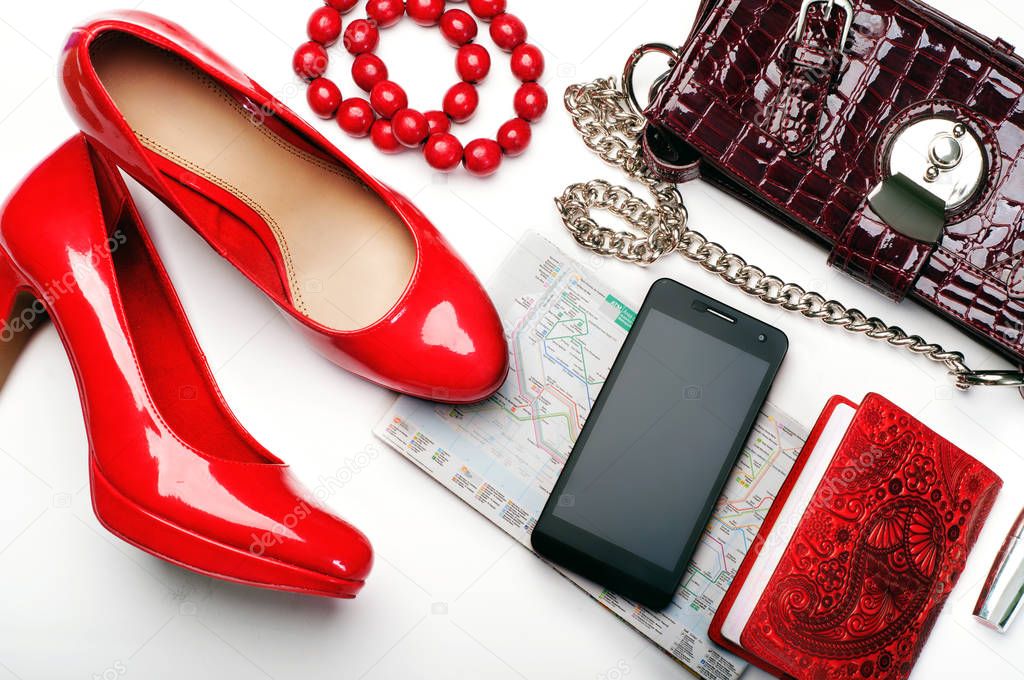 Concept let's travel! Red lacquered high heel shoes, passport in red cover, telephone, map of Barcelona and lipstick   on a white background. All you need to travel for a stylish young woman.