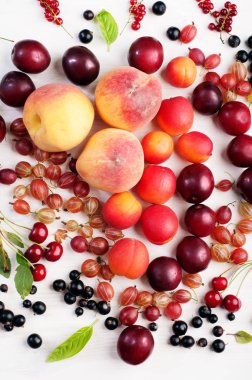 Taze olgunlaşmış meyve ve çilek şeftali, Erik, bektaşi, kırmızı ve siyah kuş üzümü ve beyaz bir yüzeye kiraz gibi. Vejetaryen, vegan gıda. Bir çiftçinin hasat kavramı