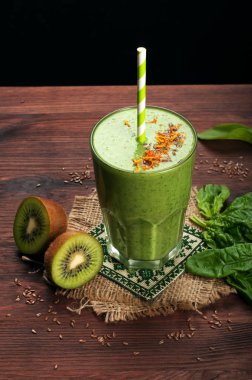 Elma, kivi, limon, ıspanak yaprakları ve yeşil çay siyah bir yüzey üzerinde dışarı yeşil smoothies (sağlıklı diyet meşrubat). Vejetaryen, vegan kavramı. Siyah arka plan üzerinde metin için yer