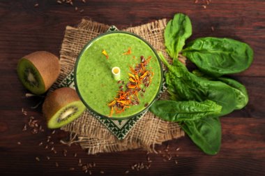 Yeşil smoothies (sağlıklı diyet meşrubat) elma, kivi, limon, ıspanak yaprakları ve yeşil çay koyu ahşap yüzeye çıkar. Vejetaryen, vegan kavramı. Makro çekim. Yukarıdan görüntülemek