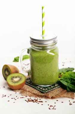 Yeşil smoothies (sağlıklı diyet meşrubat) elma, kivi, limon, ıspanak yaprakları ve yeşil çay beyaz bir yüzeye çıkar. Vejetaryen, vegan kavramı. Metin için yer
