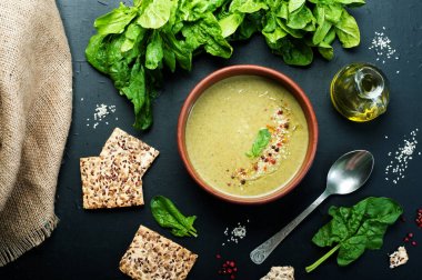 Düşük kalorili diyet çorbası ıspanak, patates, havuç ve soğan koyu arka plan üzerinde bir kil çanağı. Ispanak, zeytin yağı yapraklar ve ekmek diyet. Vejetaryen, vegan kavramı.