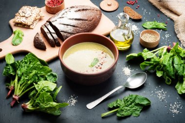 Düşük kalorili diyet çorbası ıspanak, patates, havuç ve soğan koyu arka plan üzerinde bir kil çanağı. Yapraklar ıspanak, zeytin yağı ve çavdar ekmeği. Vejetaryen, vegan kavramı.
