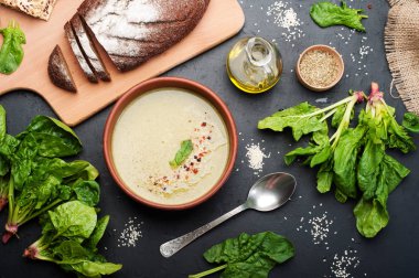 Düşük kalorili diyet çorbası ıspanak, patates, havuç ve soğan koyu arka plan üzerinde bir kil çanağı. Yapraklar ıspanak, zeytin yağı ve çavdar ekmeği. Vejetaryen, vegan kavramı.