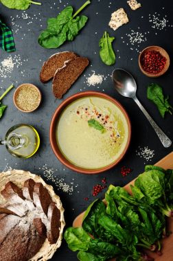 Düşük kalorili diyet çorbası ıspanak, patates, havuç ve soğan koyu arka plan üzerinde bir kil çanağı. Yapraklar ıspanak, zeytin yağı ve çavdar ekmeği. Vejetaryen, vegan kavramı.