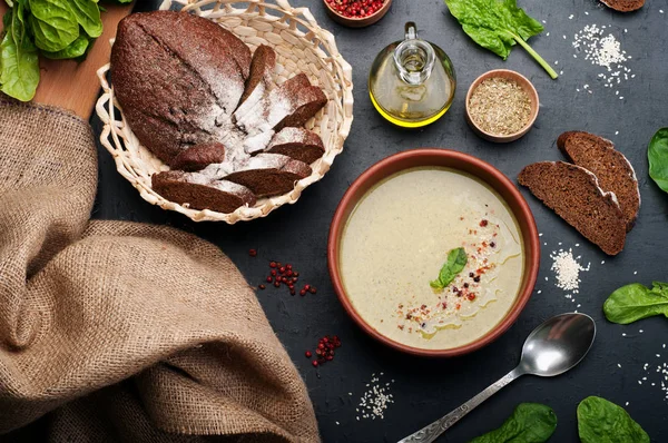 Düşük kalorili diyet çorbası ıspanak, patates, havuç ve soğan koyu arka plan üzerinde bir kil çanağı. Yapraklar ıspanak, zeytin yağı ve çavdar ekmeği. Vejetaryen, vegan kavramı. — Stok fotoğraf