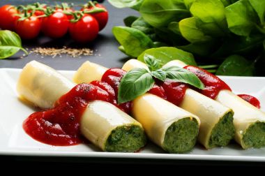 Beyaz tabakta domates soslu ıspanak ve beyaz peynir ile Canneloni (makarna peyniri ve sebze dolgu ile). Evde yararlı diyet yemek. İtalyanca, Akdeniz mutfağı
