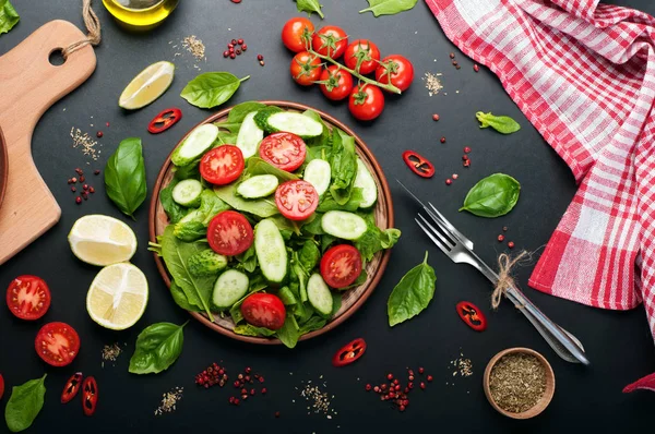 Kalorienarmer veganer Salatteller auf dunklem Hintergrund. Salat aus Spinatblättern, Kirschtomaten und Gurkenscheiben. Nützliches Abendessen. vegetarisches, veganes Konzept — Stockfoto