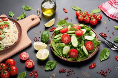 Low-calorie dietary vegan salad plate on a dark background. Salad from spinach leaves, cherry tomatoes and cucumber slices. Useful dietary dinner.  Vegetarian, vegan concept clipart