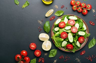 Karanlık bir arka plan üzerinde düşük kalorili diyet vegan salata tabağı. Salata dan ıspanak yaprakları, domates ve salatalık dilimleri. Yararlı diyet yemeği. Vejetaryen, vegan kavramı. Metin için yer